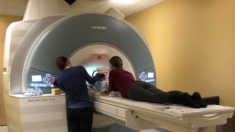 Researchers assist a participant in a CAT scan.